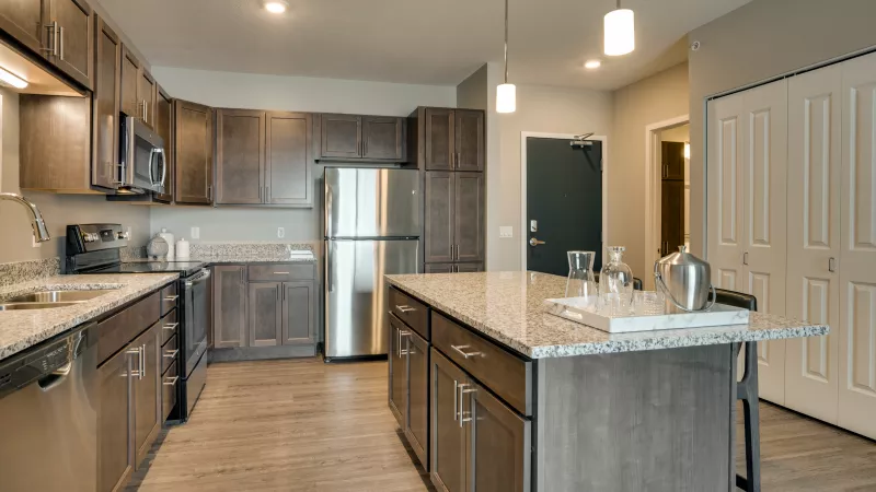 Spacious modern kitchen with dark cabinets, stainless steel appliances, light granite, and a large island.